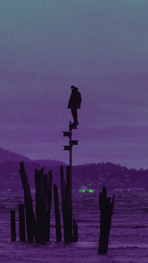 Silhouette of a person standing on a post in the water