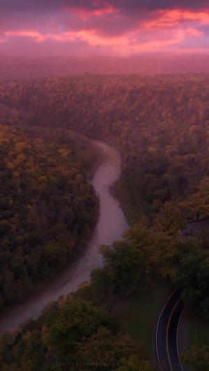 River through forest at sunset with pink clouds