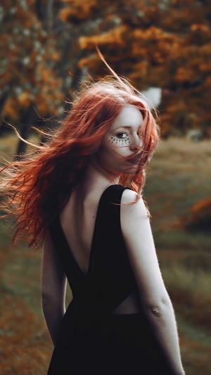 Redhead girl with face paint in black dress