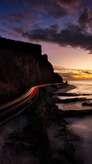 Coastal road at sunset with light trails
