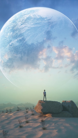 Person standing on rocks looking at a large planet