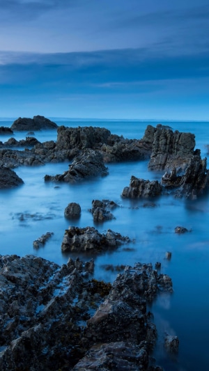 Rocky coastline at dusk with calm sea