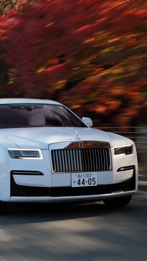 White Rolls-Royce Ghost driving in autumn