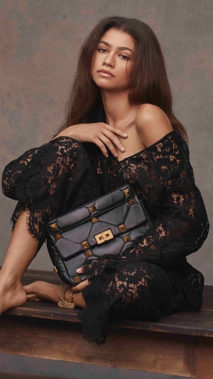 Zendaya in a black lace outfit holding a Valentino bag
