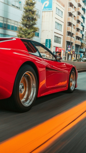 Red Ferrari Testarossa driving on city street