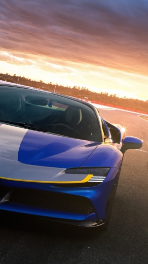 Blue Ferrari SF90 Spider on a race track at sunset