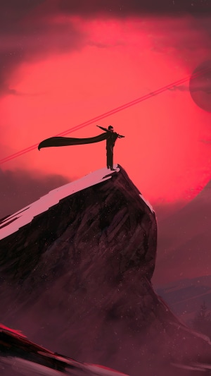 Figure with cape on mountain peak under red sky