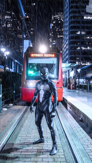 Spider-Man in black suit on train platform in rain