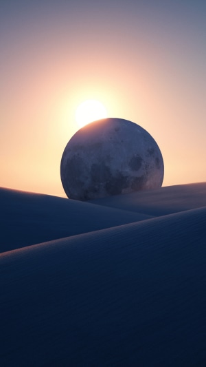 Moon over desert dunes at sunset