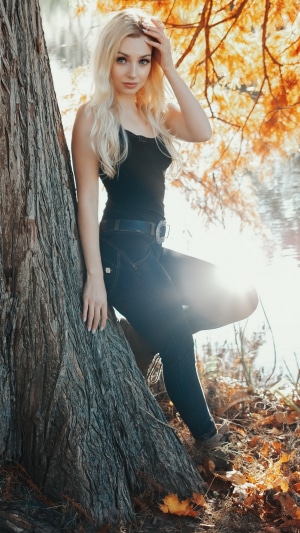 Blonde girl in autumn by a tree