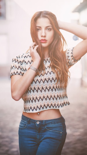 Woman with long brown hair wearing a crop top and jeans
