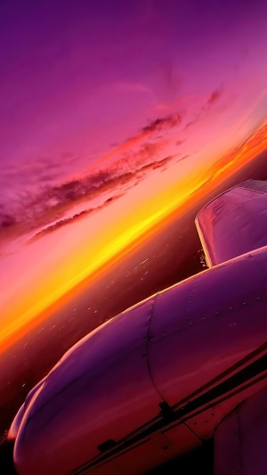 Airplane wing against a vibrant sunset sky