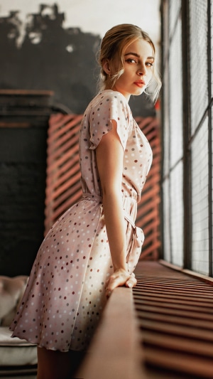 Model in polka dot dress by window
