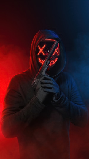 Masked figure in hoodie holding a gun