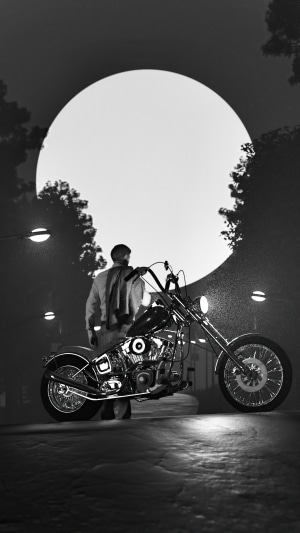 Biker with motorcycle under a large moon