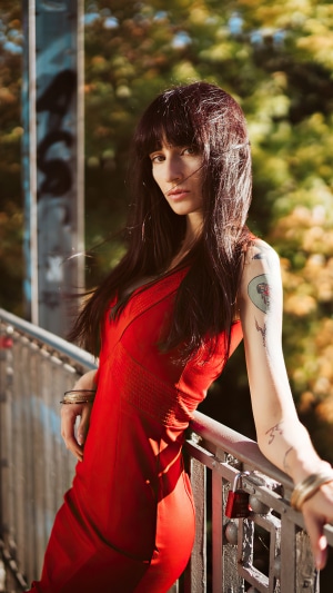 Woman with tattoos in a red dress on a bridge