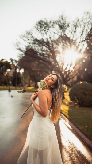 Woman in white dress holding flowers in park