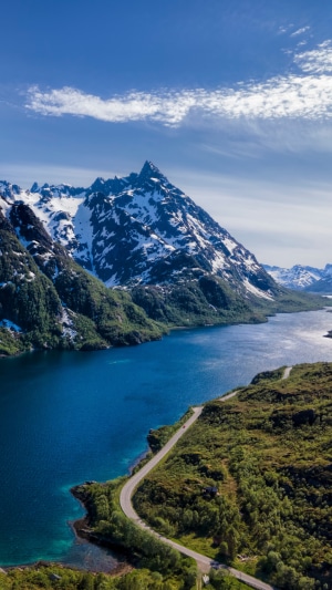 Snow-capped mountains and a lake with a road