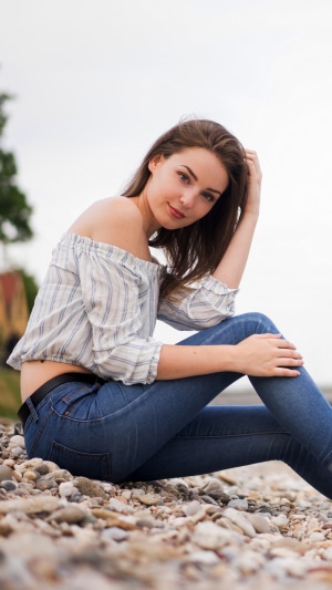 Model in off-the-shoulder top and jeans on beach
