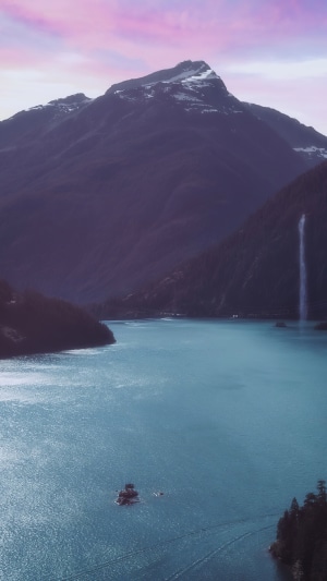 Mountain lake with waterfall and boat