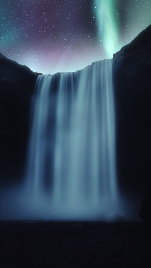 Waterfall under Aurora Borealis and stars