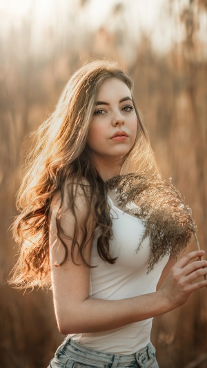 Young woman in a white tank top holding a dried plant