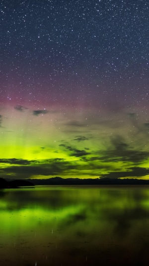 Aurora Borealis over a lake under starry sky