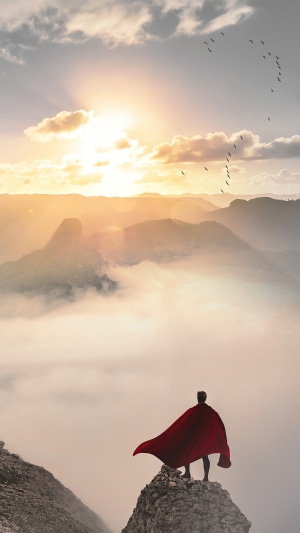 Superman standing on a mountain peak at sunrise