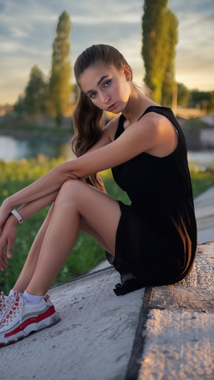 Girl in black dress sitting outdoors