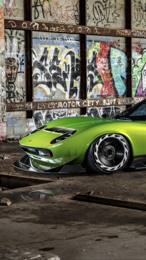 Green Lamborghini Miura in graffiti-covered garage