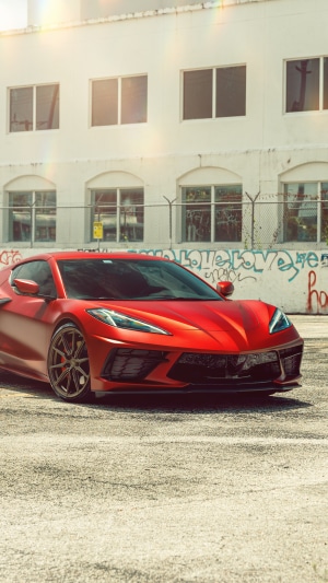 Red Chevrolet Corvette Stingray C8 parked in front of graffiti wall