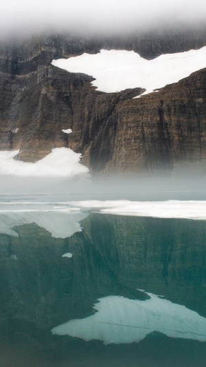 Mountain reflection in a lake with snow and fog