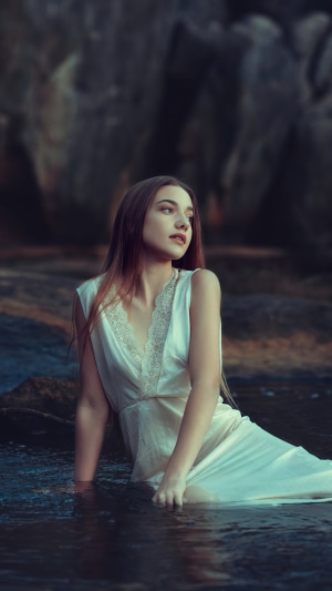 Girl in a white dress sitting in water