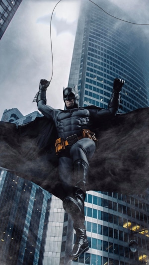 Batman in costume swinging between buildings