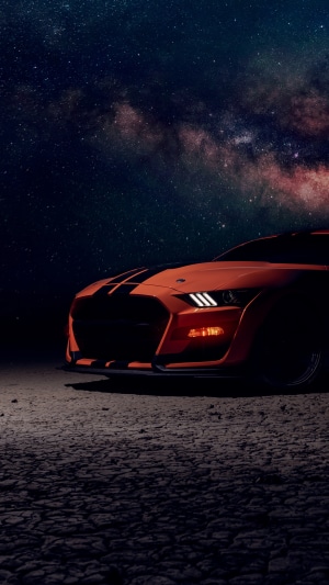 Orange Ford Mustang GT500 under starry sky