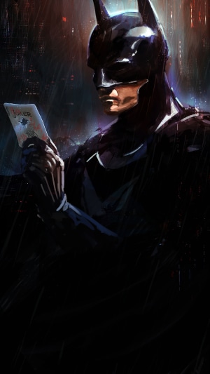 Batman holding a Joker card in the rain