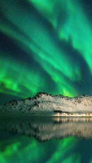 Aurora Borealis over snow-capped mountains and reflection