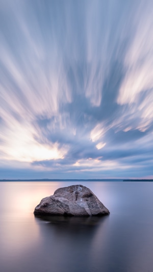 Rock in a lake with streaky clouds