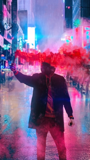 Person holding red smoke bomb in rainy city