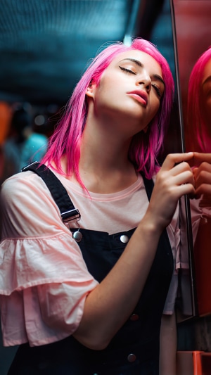 Model with pink hair wearing overalls and pink shirt