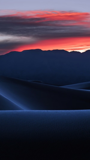 Desert dunes at sunset with mountain silhouette