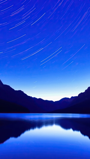 Star trails over a calm lake and mountains 4K