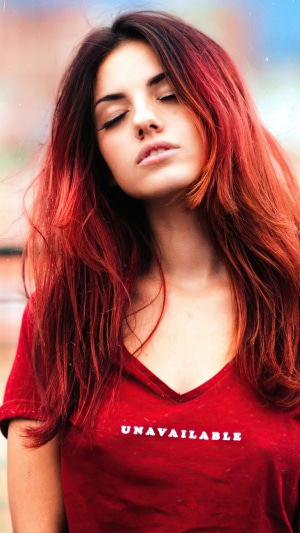 Woman with red hair wearing a red t-shirt with 'UNAVAILABLE' text