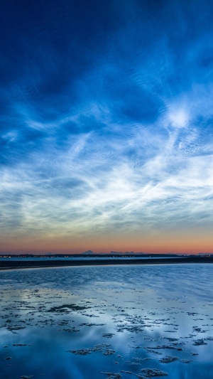 Noctilucent clouds over a body of water at dusk