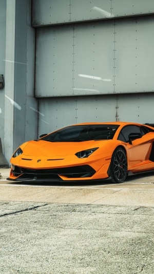 Orange Lamborghini Aventador SVJ parked in front of a building