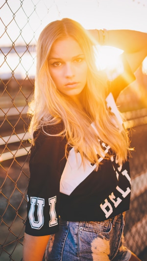 Girl in crop top and denim shorts by fence