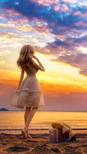 Doll on a beach at sunset