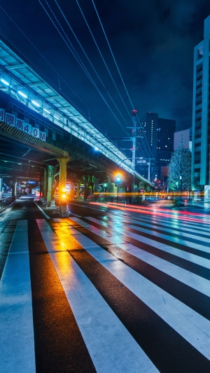 Nighttime city street with crosswalk and train tracks