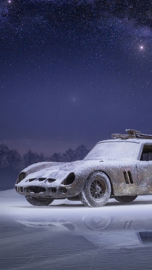 Snow-covered classic car under starry sky