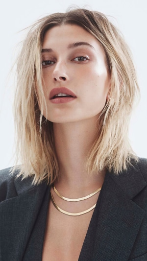 Hailey Baldwin wearing a dark blazer and gold necklaces